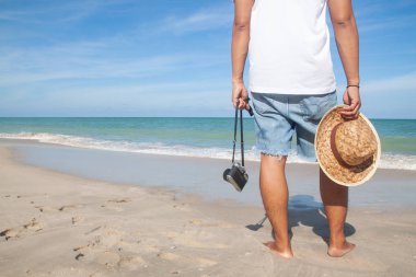 Kamera ve sahilde yürüyüş şapka ile rahat tarzı adam mutlu tatil