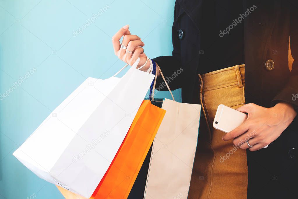 Woman in black overcoat with shopping bag and smartphone in hands. Black Friday