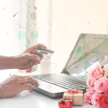 Hediye ve tablo, gül ile bilgisayar ve kredi kartı kullanan adam online alışveriş. Sevgililer günü