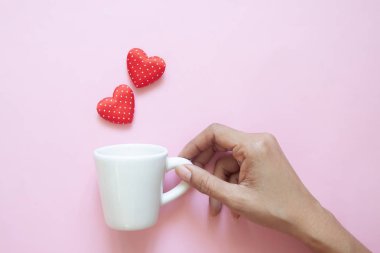 Yaratıcı düz yatıyordu, pembe polka noktaları kırmızı kalpler ile beyaz fincan tutan kadın el