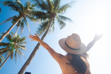 Asyalı kadın güneş şapka ile silah palmiye ağaçları ve gökyüzü ile ortaya çıkar.. 