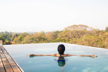 Yüzme ve Yüzme Havuzu çatı üst üzerinde rahatlatıcı Asyalı kadın