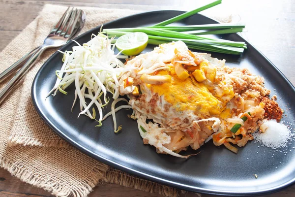 Napper les nouilles thaïlandaises ou sautées avec des crevettes et des œufs sur une assiette noire — Photo