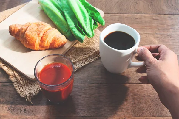 Kvinna hand med svart kaffekopp med hälsosam frukost på träbord. Välmående — Stockfoto