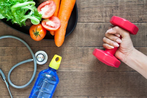 Health and fitness concept. Vegetables, fitness equipment on wooden background