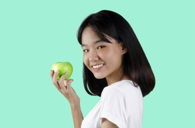 Beyaz arka plan ile yeşil bir elma tutan genç bir kız