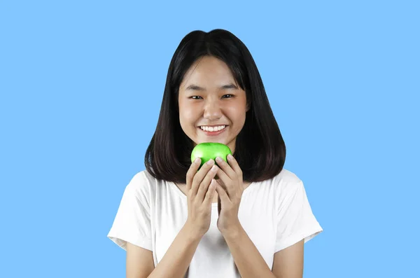 Uma jovem segurando uma maçã verde com o fundo azul — Fotografia de Stock