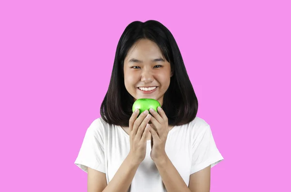 Seorang gadis muda memegang apel hijau dengan latar belakang merah muda — Stok Foto