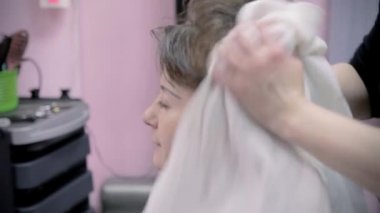 Kuaför saç modeli genç kız için yapar. Kuaför havlu kullanır