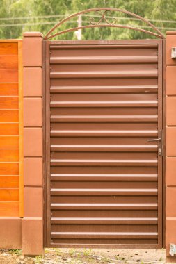 Bir küçük kapı giriş grubuyla profilli Brown bir çitle çevrili kapatma. Mimari.