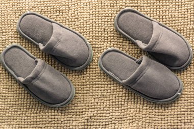 İki çift izole kahverengi bir arka plan üzerinde gri ev yapımı terlik. Ev rahatlık.