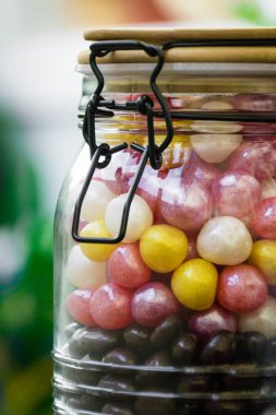 Bir dar kapak ile renkli şekerler ile büyük bir konteyner. Tatlılar