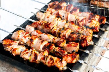 Pork skewers on skewers with an appetizing crust. Food on the coals clipart