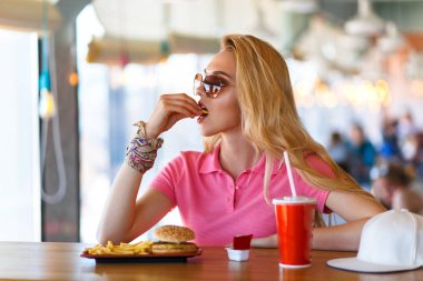 Genç ve güzel bir kadın kafede dinleniyor ve yemek yiyor.