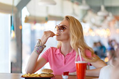 Genç ve güzel bir kadın kafede dinleniyor ve yemek yiyor.
