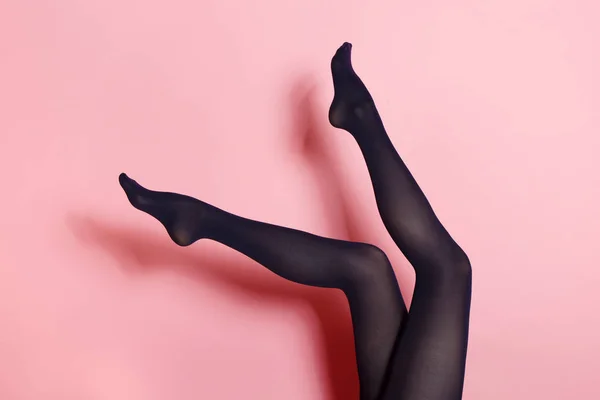 ピンク色の背景に黒タイツの若い白人女性の足 — ストック写真