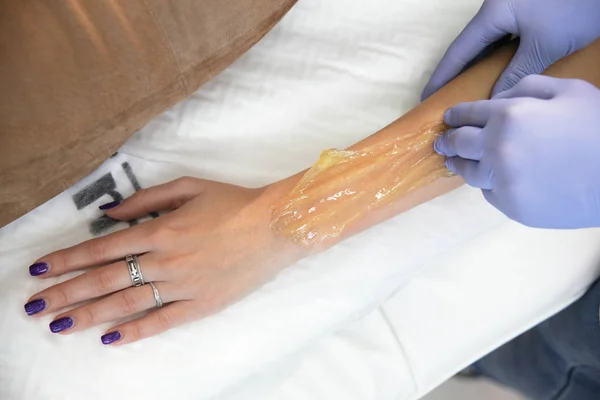 Schoonheidsspecialiste verwijdert haar van een vrouw hand. — Stockfoto