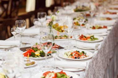 Ziyafet masasına servis edilmiş. Peçeteli, bardaklı ve salatalı şarap bardakları.