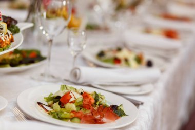 Ziyafet masasına servis edilmiş. Peçeteli, bardaklı ve salatalı şarap bardakları.