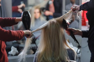 Saç kurutma makinesi saç sarışın model güzellik salonu ile aynı anda iki efendiye kurumuş. Arkadan Görünüş.