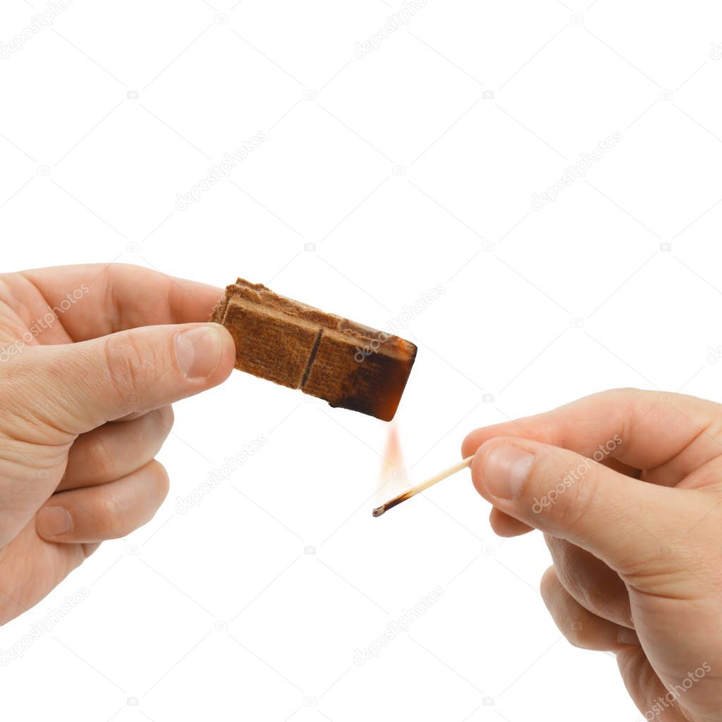 Hands of the man who burns solid firelighter for barbeque. Isolated on white background.