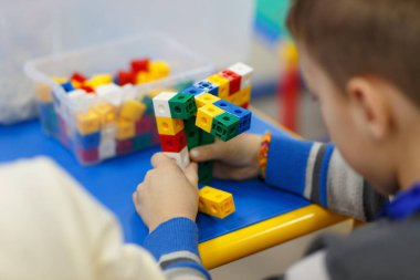 Çocuğun Ellerin masada renkli plastik tuğla ile oynarken kapatın. Mühendislik tür düşünme geliştirilmesi için ilk adımlar.