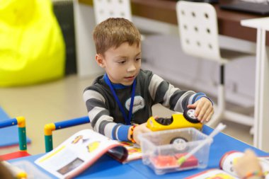 Çocuk bir radyo kontrollü araba modelinin dijital teknolojilerin okulda bir elektronik-mekanik tasarımcı bloklarını toplar. Onun çalışma öğretmen tarafından kontrol edilir.