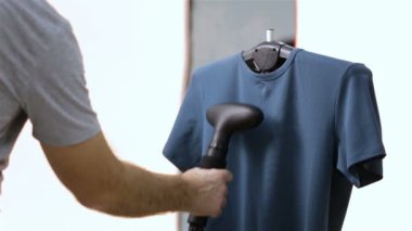 Bir adam bir dükkanda bir ev vapuru ile bir t-shirt buharlarının