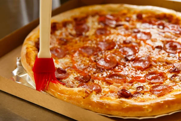 The chef prepares pizza lubricating oil with a cooking brush