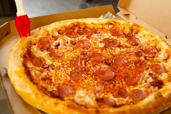 The chef prepares pizza lubricating oil with a cooking brush