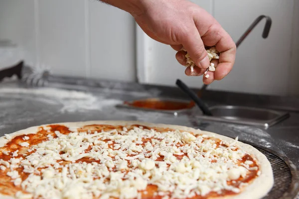 Şefin elleri peynir ile pizzayı Sprinkles