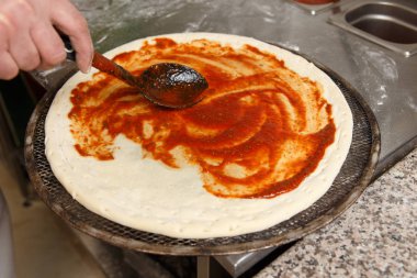 Bir pizza üzerinde kepçe tarafından domates sosu dökme Cherif 