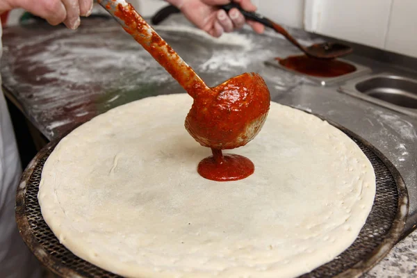 Чиф, що наливає томатний соус на ковбасу на піцу — стокове фото