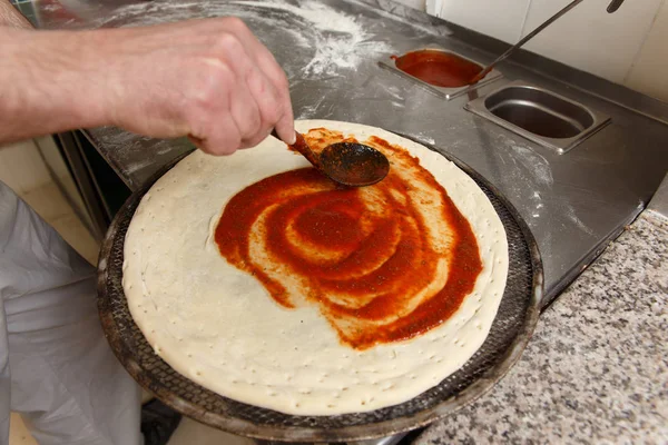 Bir pizza üzerinde kepçe tarafından domates sosu dökme Cherif 