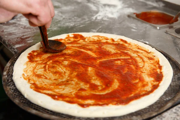 Bir pizza üzerinde kepçe tarafından domates sosu dökme Cherif 