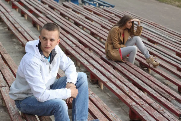 Szomorú fiú és egy lány ül tribunusok az üres stadion. — Stock Fotó