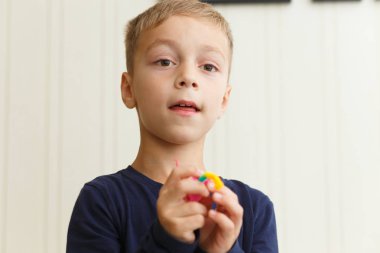 Boy weaves bracelet of rubber rings 