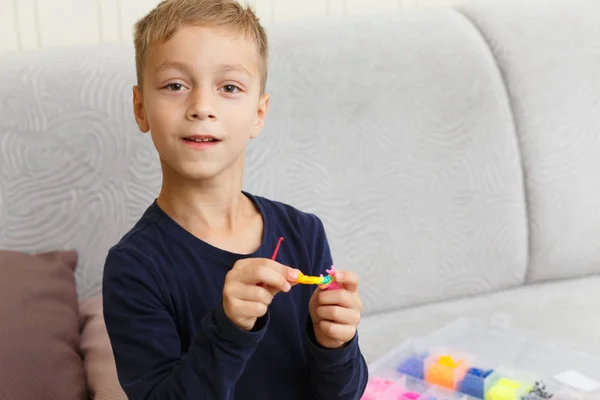 Boy weaves bracelet of rubber rings — Stockfoto