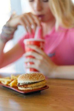 Genç ve güzel bir kadın kafede dinleniyor ve yemek yiyor.