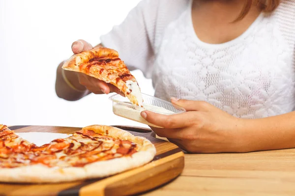 Bir kız yemeden önce bir dilim pizzayı plastik bir kaba bandırıyor.