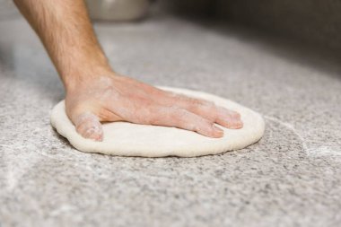 Masa arkasında erkek eli ile para kazanmak. Pizzacı pizza hamuru hazırlıyor..