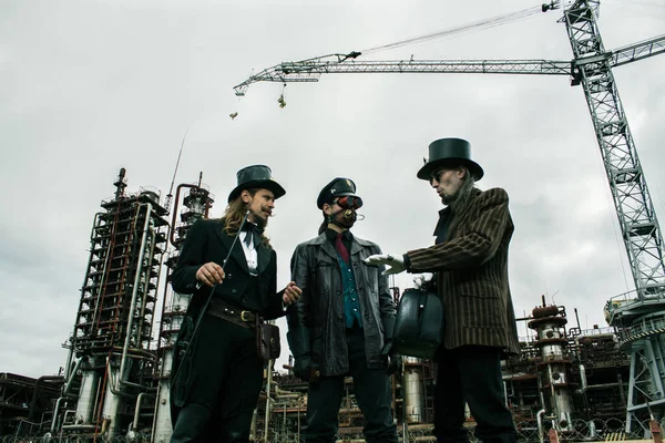 Tres Hombres Estilo Steampunk Discuten Pie Contra Trasfondo Industrial — Foto de Stock