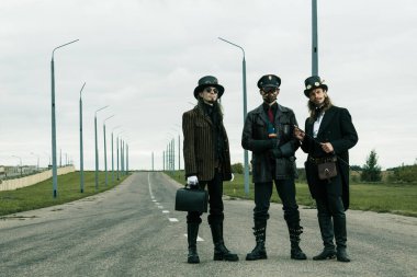 Steampunk tarzı üç adam yolda poz veriyor.