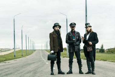 Steampunk tarzı üç adam yolda poz veriyor.