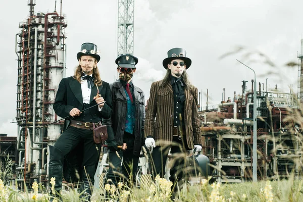 Τρεις Άνδρες Στυλ Steampunk Στέκεται Πάνω Στο Βιομηχανικό Υπόβαθρο — Φωτογραφία Αρχείου