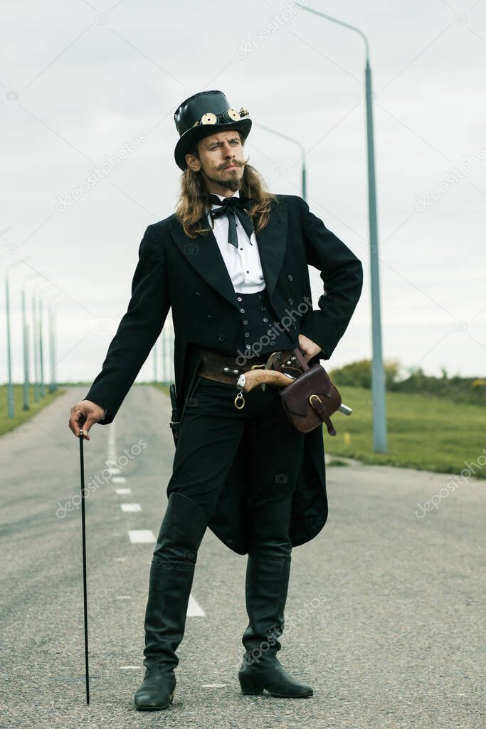 Young man weared in steampunk style posing on the road