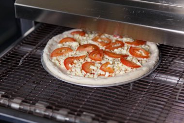 Çiğ pizza bir restorandaki modern fırına teslim edilir.