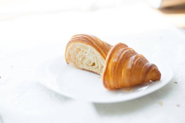 Taze pişmiş kruvasan beyaz tabakta parçalara ayrılmış.