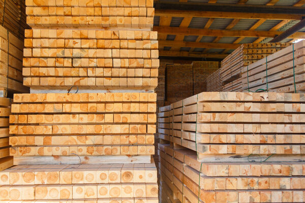 Piles of wooden boards in the sawmill, planking. Warehouse for sawing boards on a sawmill outdoors. Wood timber stack of wooden blanks construction material. Lumber Industry.