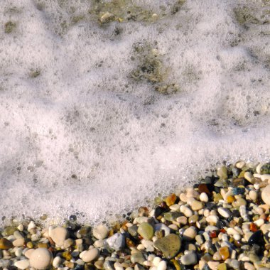 Deniz suyu, köpüklü dalgalar sırılsıklam Parlatıcı ve birçok renkleri al küçük deniz çakıl                               